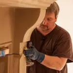 Installers installing fireplace mantel by Old World Stoneworks