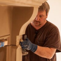 Installers installing fireplace mantel by Old World Stoneworks